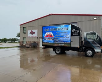 Mobile advertising truck parked at business featuring client digital signage campaign on LED truck