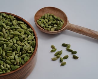 Green Cardamom placed in Wooden Tumbler and a wooden spoon