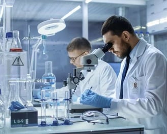 two men in lab coats and lab coats are looking at a microscope