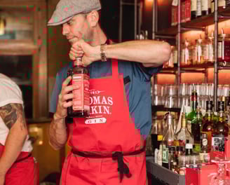 Thomas Dakin representative opening a bottle of gin.