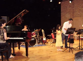 a group of people standing around a piano