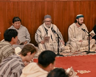 a group of men sitting on a carpeted area remembering Allah