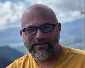 a man with a beard and glasses on a mountain