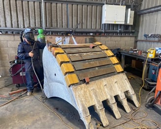 a man welding a piece of wood with a welding machine