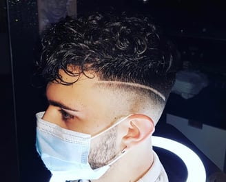 Taglio sfumato con riga incisa e capelli ricci.