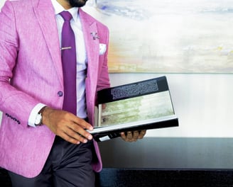 a man in a pink suit and tie is holding a book