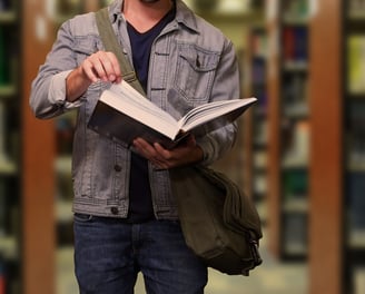 a man in a jacket and jeans is holding a book