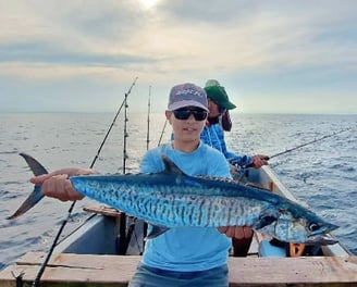 A happy beginner angler holding a fish on a boat in Zanzibar