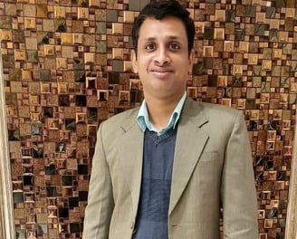 a man in a suit and tie standing in front of a wooden paneled wall
