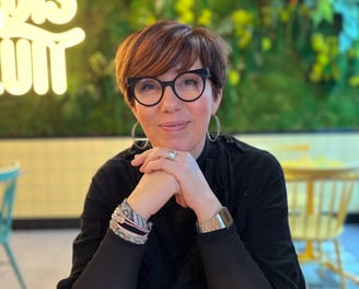 Portrait de Laurence Boukraa. Elle sourit les coudes sont posés sur une table