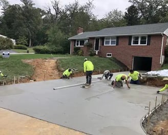 a group of men in yellow jackets and yellow jackets working on a concrete slab