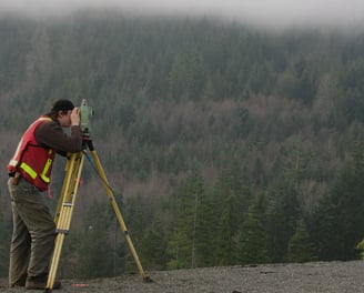 a man in a red vest and a yellow vest is holding a tripod