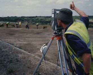 a man in a yellow vest and a camera on a tripod