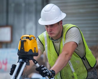 a man in a hard hat and safety vest holding a laser level