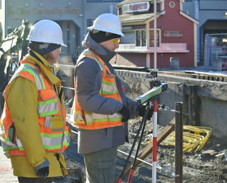 a man in a red vest and a yellow vest is holding a tripod