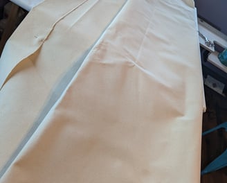 10 oz linen folded and laid on a large artist's table for folding and pinning.,