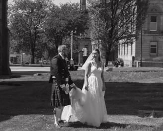 a bride and groom in a field with a scottish flag