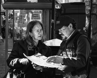 A woman tourist chats with a tour guide, who is holding a map, looking for directions. Waterloo Place, Edinburgh