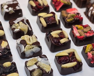 Artisan dark chocolate squares topped with dried fruits and nuts, handcrafted for elegant gifting and