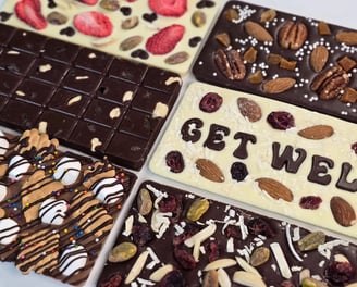 Custom Handcrafted gourmet chocolate bars topped with dried fruits and nuts, elegantly arranged for gifting or indulgence.