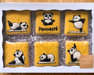 Set of decorated cookies in a box featuring adorable panda-themed, crafted with royal icing, a unique treat for yoga lovers