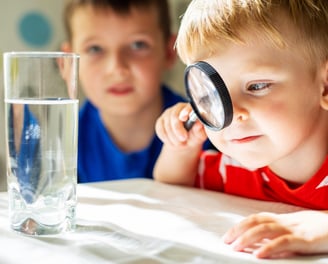 a boy looking through a magnifying glass at Reno preschool