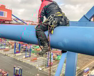 a man in a helmet and safety gear on a crane