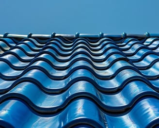 A Clean and wavy blue tile roof on a clear day reflects the same clear blue sky