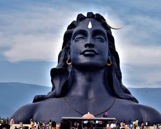 Lord Shiva statue with people gathering for darshan and pooja