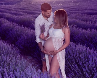 futuros papas mirandose con ternura  en  exterior y campos de lavanda, con ramo de flores en mano  