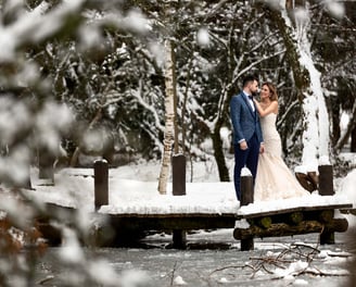 a bride and groom standing on a bridge over a river