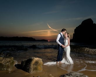 a bride and groom standing in the ocean