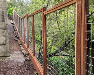 a tall hogwire redwood fence along a home