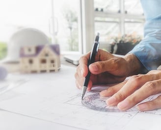 gros plan main écrivant sur un plan de construction