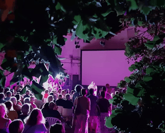 a crowd of people standing in front of a screen