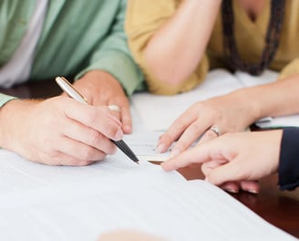 a couple signing a house purchase with a notary loan signing agent instructing where to sign