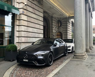 Two sports cars parked outside of an hotel