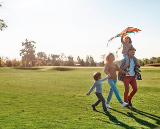 Familia tradicional con dos hijos caminando felices por el campo de golf de Bosque Real