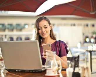 Empreendedora cuidando da gestão do seu negócio, utilizando notebook e celular.