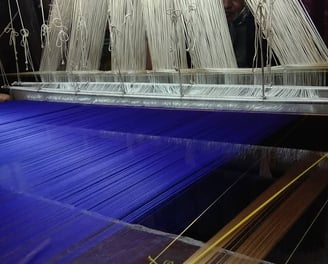 a man is working on a blue and white weaving machine