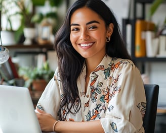 Mujer joven sonriendo enfrente de su laptop, trabajando desde casa y generando ingresos.