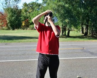 Homme avec t-shirt rouge prenant une photo.