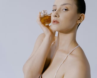a woman in a white shirt dress posing with a perfume bottle