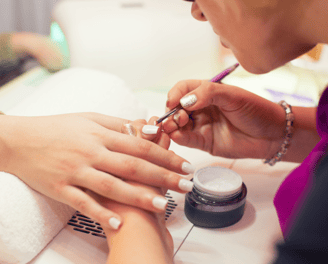 A lady receiving a nail treatment from a meticulous manicurist