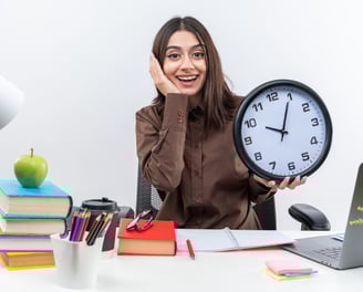 A young student holding a clock while studying depicting time management 