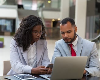 Two business professionals reviewing information on a laptop, representing administrative and legal support for enterprises.