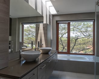 fotografía inmobiliaria quito ecuador tumbaco baño elegante y sobrio con dos lavabos y vista a un árbol
