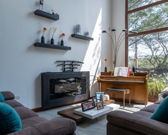 fotografía inmobiliaria quito ecuador tumbaco gran sala de estar con muebles, piano y un gran ventanal con luz natural