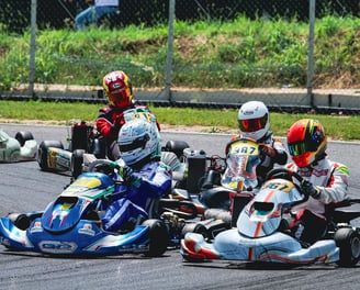 Quatre karts serrés sur une piste, pilotes en position compétitive lors d'une course.