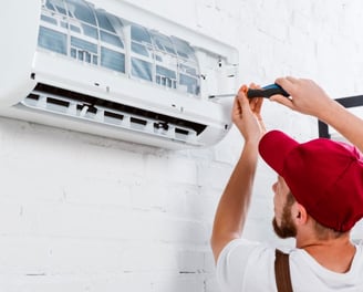 a man in a red hat is fixing a air conditioner